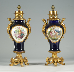 899.  Pareja de “pot-pourries” de porcelana esmaltada en azul real, decorada en reservas con  flores por una cara y por otra con ninfas, sátiros y una alegoría del Amor.Francia, S. XIX..