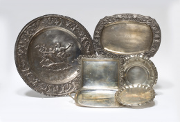 1086.  Lote de cuatro bandejas de plata: un panera de Matilde Espuñes (Madrid, 1909-1950), una salvilla siguiendo modelos del S. XVIII, una bandeja con asas y una bandeja con alero de estilo renacentista repujado.España, pp. del S. XX..