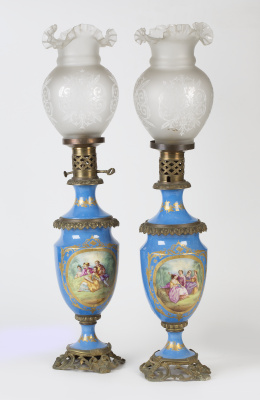 1214.  Pareja de quinqués a la manera de Sévres, en porcelana esmaltados en azul con cartelas de escenas galantes y montados en metal.Trabajo francés, h. 1900