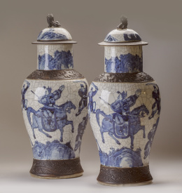 1127.  Pareja de tibores con tapa en porcelana blanca y azul craquelada, decorados con guerreros.China, ff. del S. XIX - pp. del S. XX.