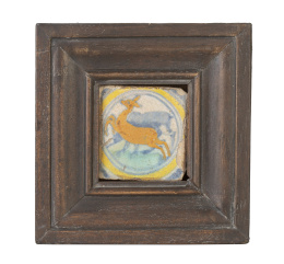 1085.  Olambrilla de cerámica esmaltada en ocre, amarillo y verde con un ciervo, inserto en un círculo.Triana, S. XVIII.